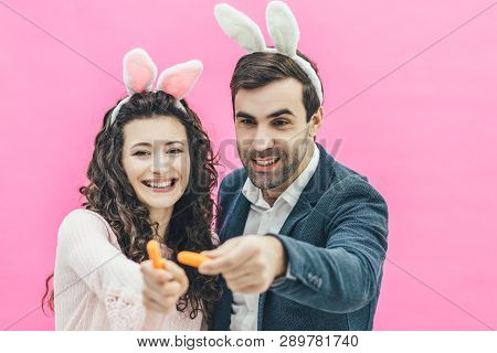 Young Beautiful Couple Standing On A Pink Background. During This Man And His Wife Hold Small Isolat