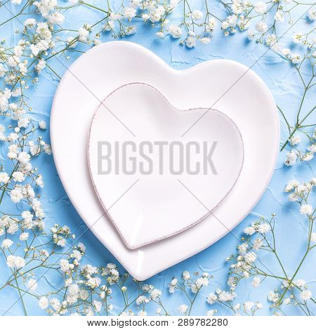 Plates In Form Of Hearts And  Fresh White Gypsofila  Flowers On Blue Textured Background. Top View. 