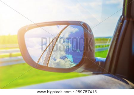 Blue Sky With Clouds In The Sideview Mirror Of A Car, On Road Countryside. Travel Natural Advanture 