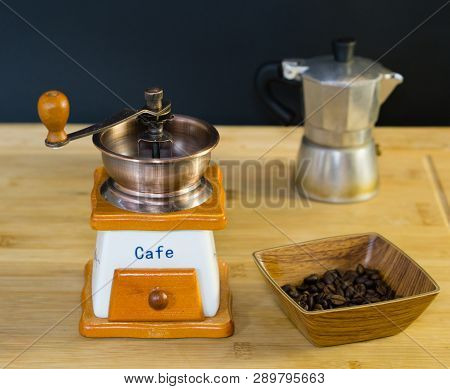 Coffee Grinder And Roasted Coffee Beans From The Side In A Wooden Dish, Moka Coffee Machine In The B