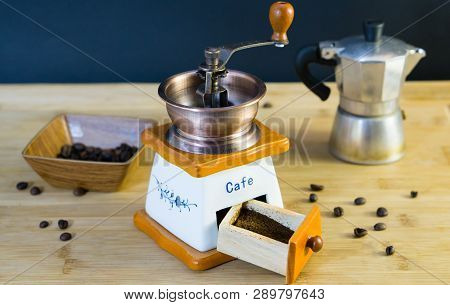 Old Italian Coffee Grinder Close-up And Already Grated Fresh Coffee, In The Background A Moka And Co