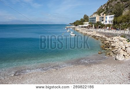 Beautiful Landscape With Azure Sea And A Pebbly Beach Near The Embankment Of The Greek Resort Of Lou