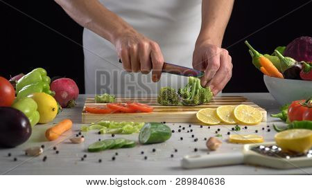 Man Is Cutting Broccoli On The Cutting Board