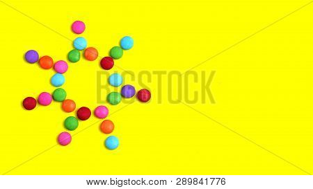 Colorful Chocolade Smarties On The Yellow Background . It Is Sun Shape.