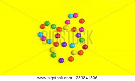 Colorful Chocolade Smarties On The Yellow Background . It Is Sun Shape.