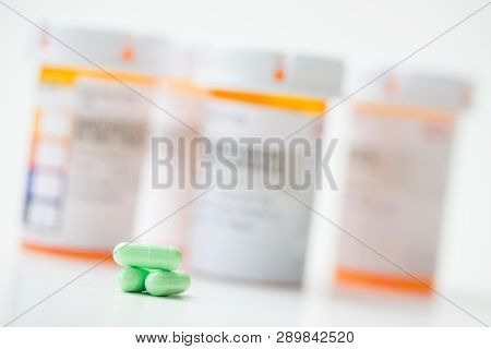 Prescription Medicine Green Capsules With Orange Pharmacy Bottles In The Background
