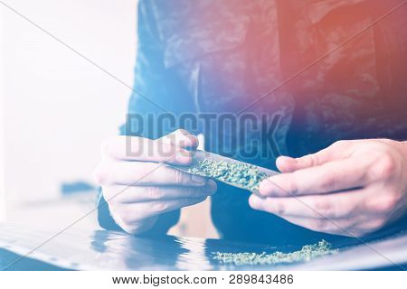 Close Up Of Addict Lighting Up Marijuana Blunt With Lighter. Man Rolling A Marijuana Blunt Drug Use.