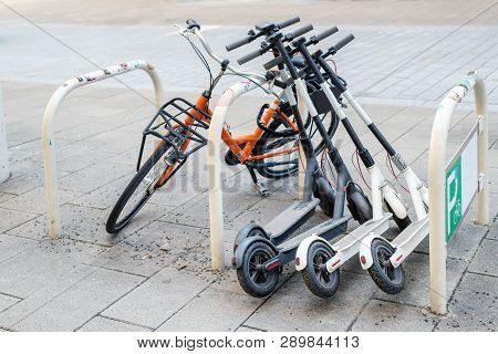 Bicycle And Electric Scooters Parked On City Street. Self-service Street Transport Rental Service. R