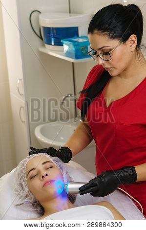 Hardware Cosmetology. Ultrasound Chromotherapy. Beautician Carries Out Procedure For Tightening Skin