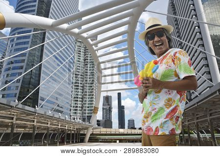 Happy Elderly Traveler Asian Man Wearing Summer T-shirt, Straw Hat And Sunglasses Holding Colorful W