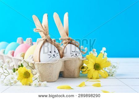 Easter Colored Eggs In Paper Tray With Decorationd On Blue Background