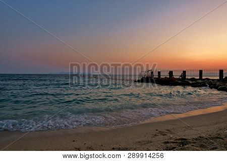 Pink-purple Sunset On The Beach With Blue Waves