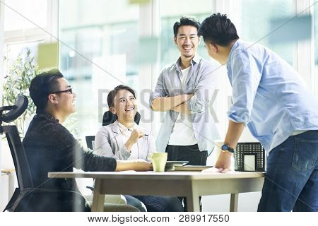 Group Of Four Happy Young Asian Corporate People Teammates Meeting Discussing Business In Office.