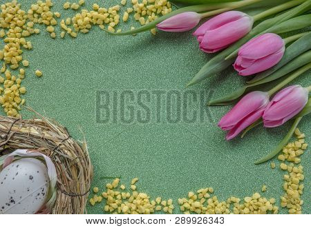 Easter Background With Pink Tulips, Yellow Sand Frame And Egg On Green Glitter Background With Copy 