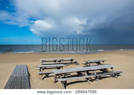 Wooden Tables And Benches Of A Summer Cafe On A Deserted Beach In The Bright Sunny Day Of The Beginn