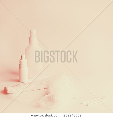Two White Medicine Bottles Big And Little, Roller Bandage And Three Cotton Buds On The White Backgro