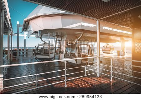 Boarding Area Of A Modern Funicular Ropeway Lit By Evening Sun With Three Cabins Waiting For Their P