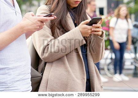 Hip Young Couple Looking At Smartphone On Shopping Trip On A Sunny Day In The City. Beautiful Young 