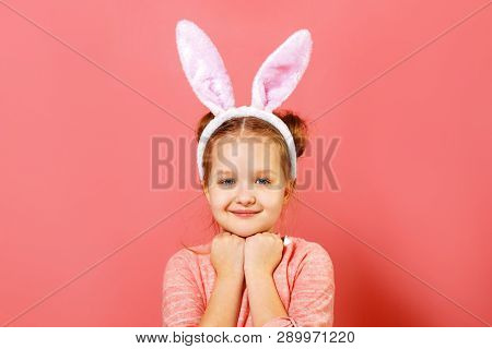 Portrait Of A Cute Little Child Girl With Bunny Ears On A Colar Pink Background. Easter Concept. Clo