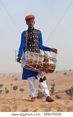 Indian Drummer In Traditional Clothes Playing In Desert