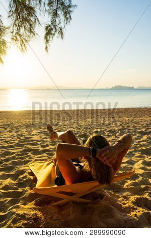 Woman enjoying her holidays on a transat at the tropical beach in Thailand at sun down