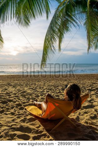 Woman enjoying her holidays on a transat at the tropical beach in Thailand at sun down