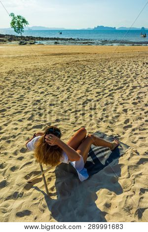 Woman enjoying her holidays on a transat at the tropical beach in Thailand