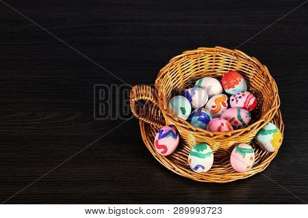 Easter Eggs In The Basket. Wicker Basket Of Straw. Festive Meal On A Dark Wooden Table.