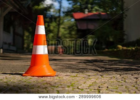 Striped Plastic Road Sign For Parking On The Pavement On The Blurred Background. Orange Traffic Road