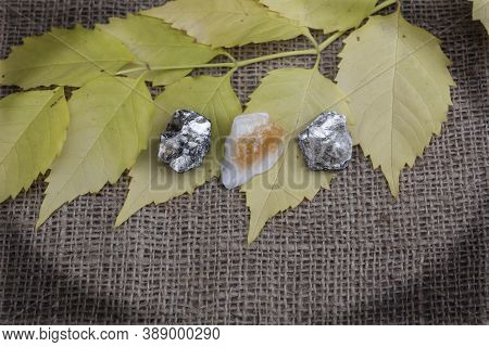 In An Oval Frame With Darkened Corners, The Semi-precious Stones Citrine And Two Phlogopites Lie On 