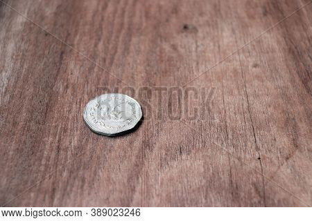 5 Baht In Nonagon Shape Of Ancient Thai Money In Reverse Of A Coin With Garuda Form On The Wooden Fl