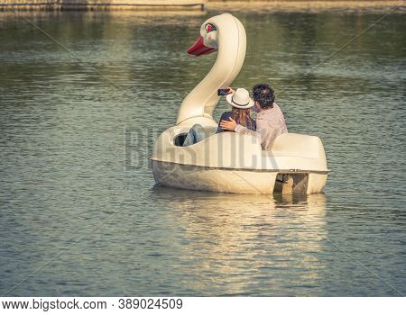 Couple Relaxing And Taking A Selfie On A Pedal Boat In Shape Of A Swan In Alexandru Ioan Cuza Park.