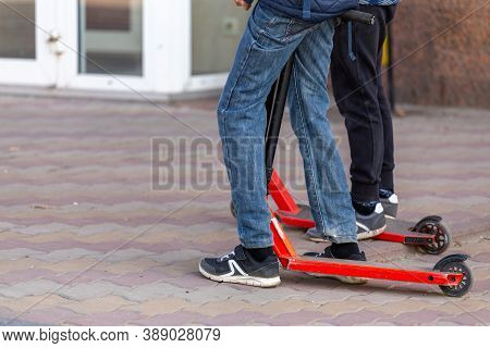 Slim Kids Legs With Scooters On The Urban Pavement Sidewalk - Closeup Witn Selective Focus