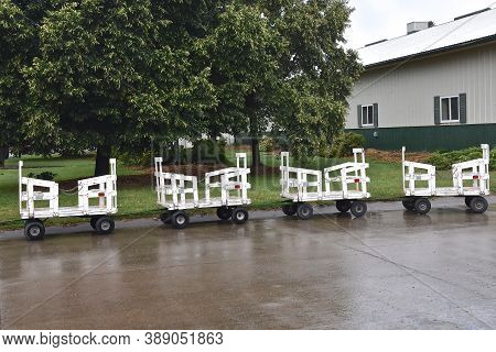 Mini Hayracks Used As People Movers Are Parked During Rain At A Fairgrounds Festival.