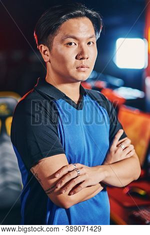 Vertical Shot Of Young Asian Guy, Male Cyber Sport Gamer Keeping Arms Crossed And Looking At Camera 