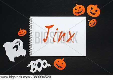 Happy Halloween Holiday Concept. Notepad With Text Jinx On Black And Orange Background With Bats, Pu