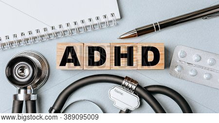 Wooden Block Form The Word Adhd With Stethoscope, Pills, Notepad, Pen On The Doctor's Desktop. Medic