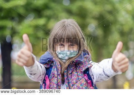 Girl Wearing Face Mask During Corona Virus And Flu Outbreak. Back To School Concept, Thumbs Up For S