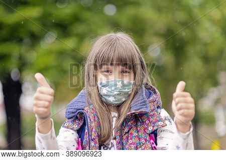 Girl Wearing Face Mask During Corona Virus And Flu Outbreak. Back To School Concept, Thumbs Up For S