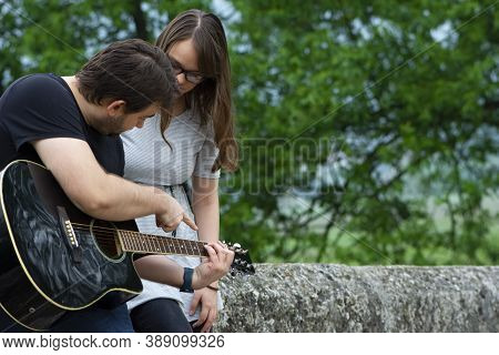 Older Brother Teaching His Younger Sister To Play Guitar In The Nature. Beautiful Moments Spent Toge
