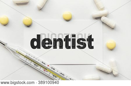 On White Business Card The Inscription Dentist In Black Letters. Near Tablets And Capsules. Thermome