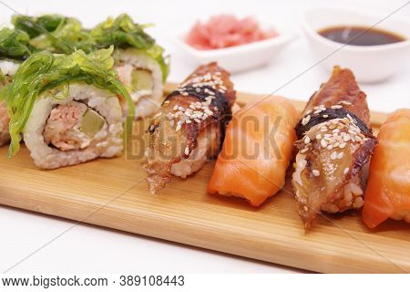 Japanese Sushi Food On A Wooden Tray, Served With Ginger, Soy Sauce And Seaweed Salad. Salmon Nigiri