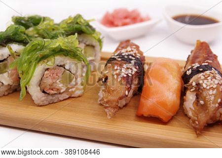 Japanese Sushi Food On A Wooden Tray, Served With Ginger, Soy Sauce And Seaweed Salad. Salmon Nigiri