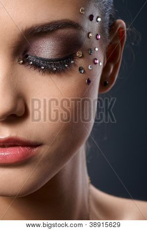 Retrato facial parcial de usar maquillaje de lujo hermosa mujer con strass, ojos cerrados.
