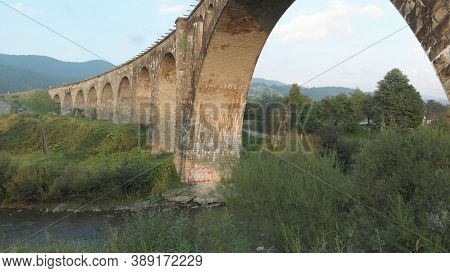Old Austrian Bridge At The Karpatian Mountains. Clear Mountain River Under Bridge View From Down.