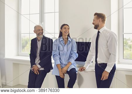 Young Smiling Business People Looking At Each Other In Office During Startup Or Project Discussion