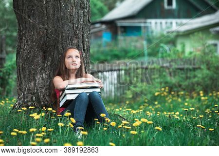 Tired teengirl with the books in the park.