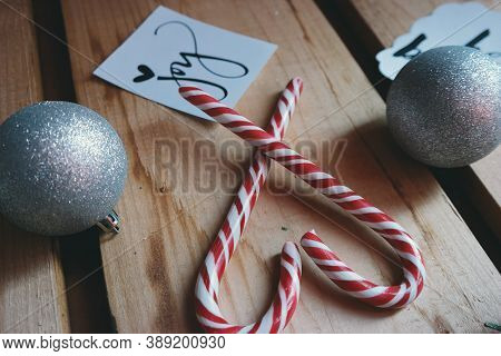 Two sticks and a Christmas ball on a wooden table with joy on a sheet of paper