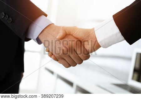 Businessman And Woman Shaking Hands In Sunny Office, Close-up. Concept Of Handshake As Success Symbo