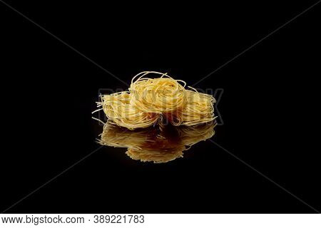 Dry, Raw Egg Pasta Capelli , Isolated On Black Background. Cooking Concept. Top View With Copy Space